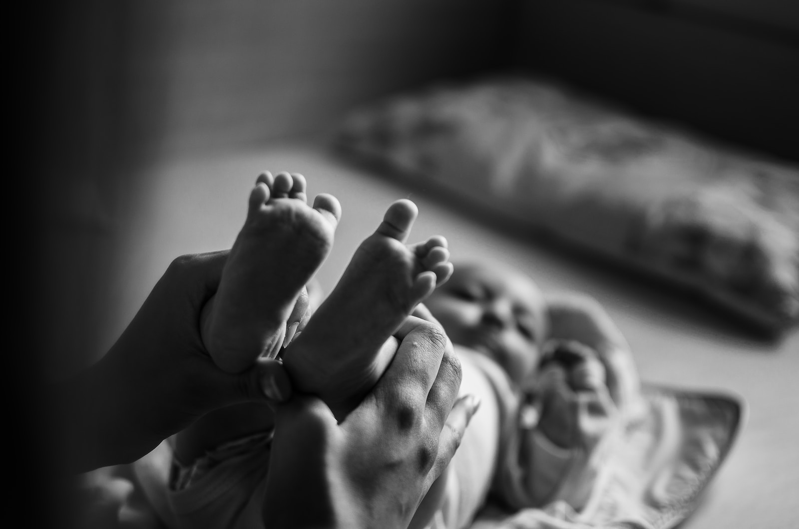 grayscale photo of persons feet on bed